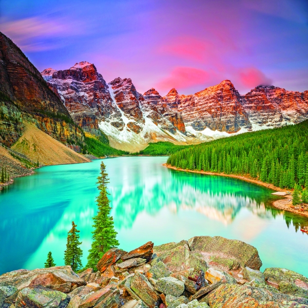 Steep, red mountains and a thick evergreen forest surround a calm light blue lake.
