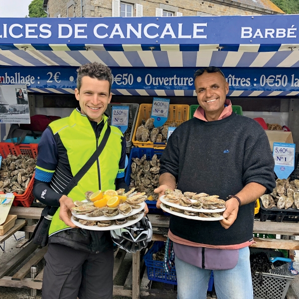 Trip leader sharing plates of local oysters on France bike tour